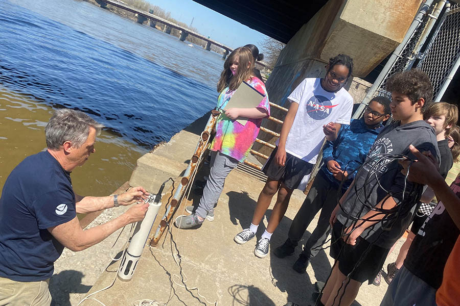 Students and teacher about to use the Hydrolab at the edge of the large river.