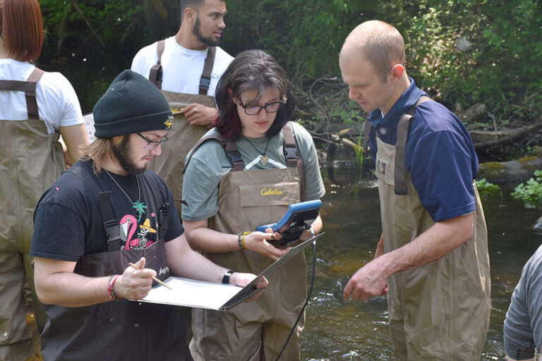Students in stream using Hydrolab equipment.